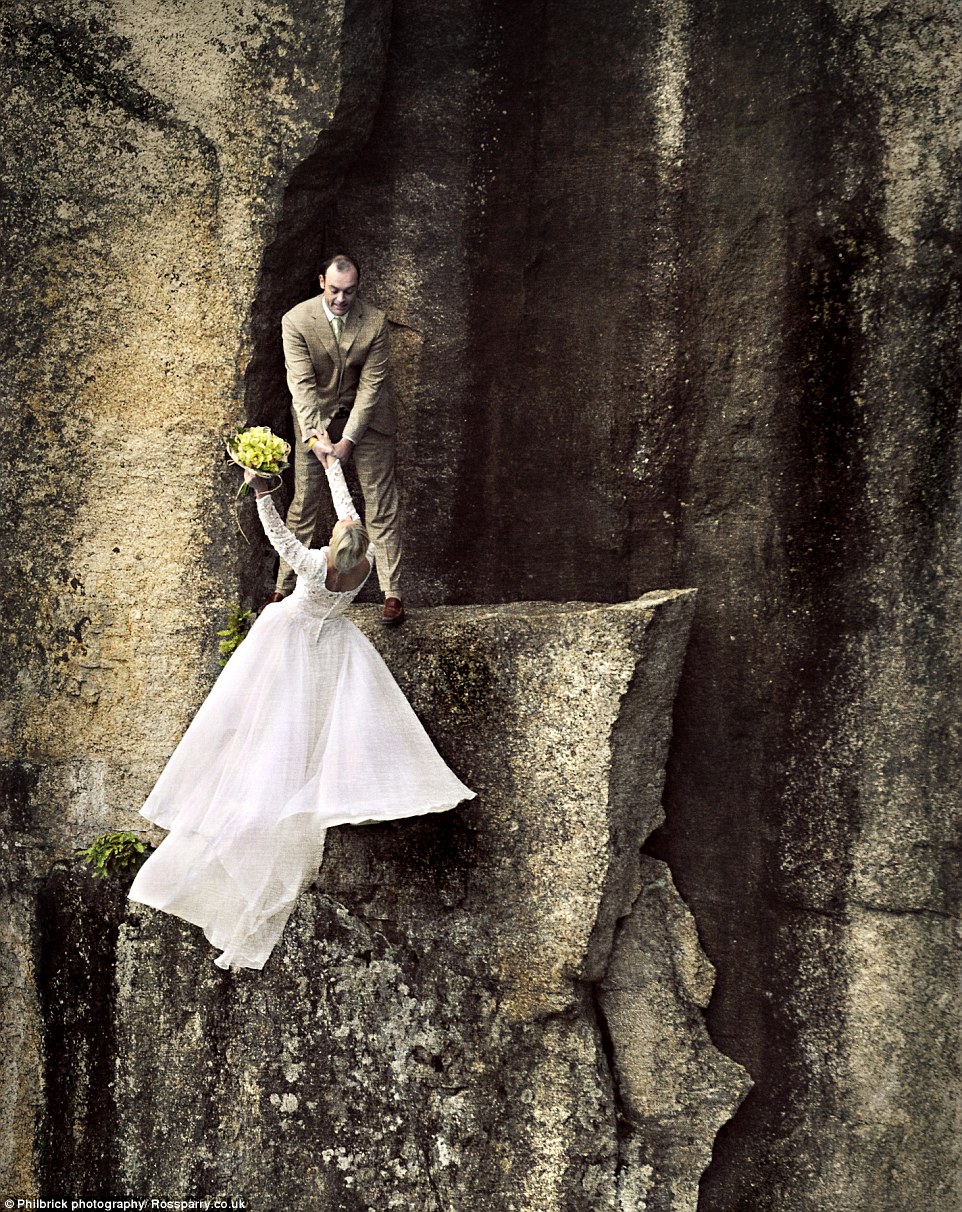 Bride Christie leans back from the rocky ledge as her new husband grips her hand tightly. Both are tied into a hidden anchor on the ledge so there's no danger of slipping�