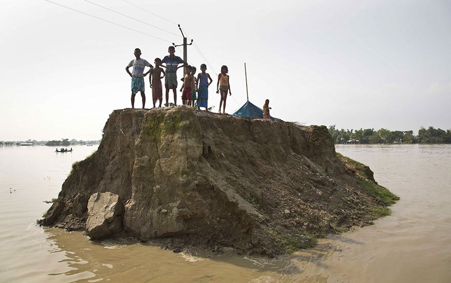 Flood-Affected Villagers Wait For Relief Material On What's Left Of A Road Washed Away By Floodwaters In Morigaon District, East Of Gauhati, Northeastern State Of Assam