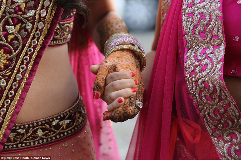 The bride's hand was adorned with an intricate orange and brown design henna tattoo as well as a number of bracelets and her engagement ring�