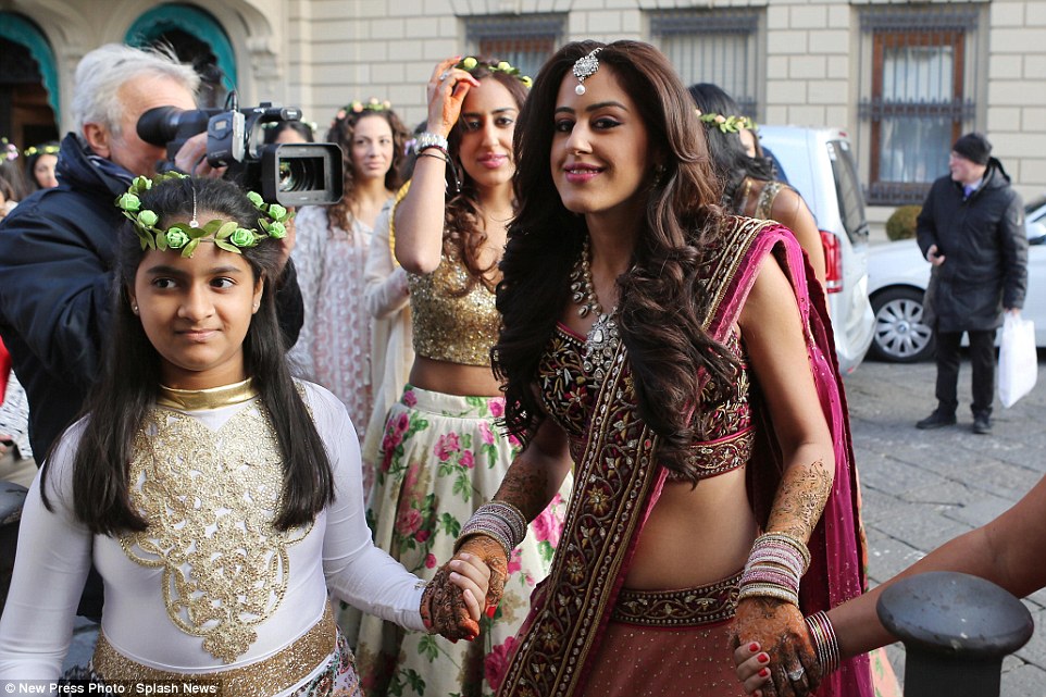 Roshni smiles for the camera and holds hands with a younger girl as she makes her way from the hotel in Florence where she has been staying