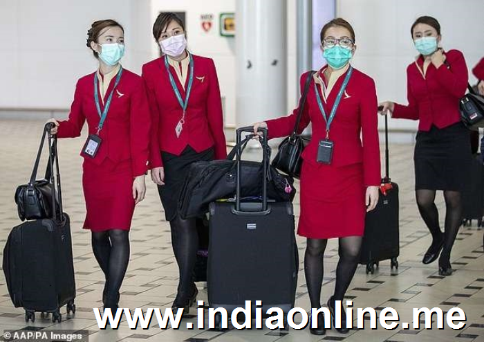 a group of people posing for the camera: Qantas (airline staff pictured on Friday) revealed plans to suspend its direct flights to mainland China